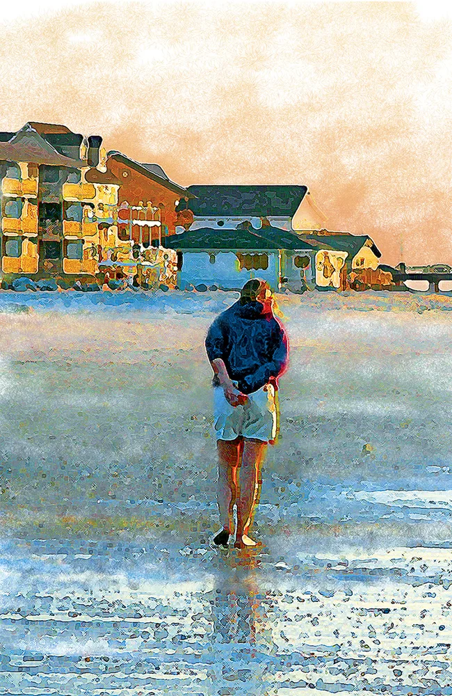 A woman taking a walk on the beach with her back turned to the camera