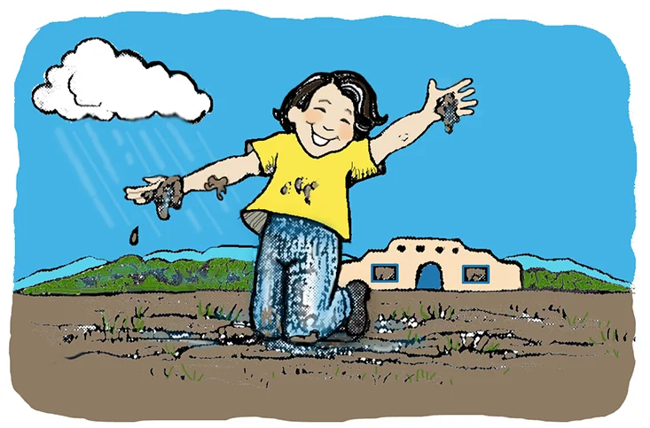 A child playing in the mud with an adobe home in the background.